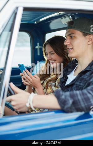 MODEL RELEASED. Young couple in a car, woman using smartphone. Stock Photo