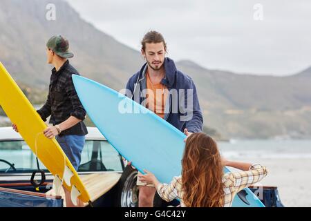 MODEL RELEASED. Young woman handing surfboard to man. Stock Photo