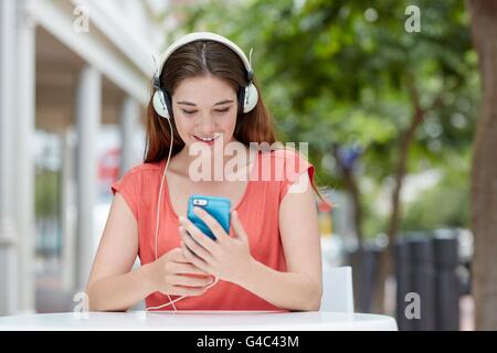 MODEL RELEASED. Young woman wearing headphones listening to music on smartphone. Stock Photo