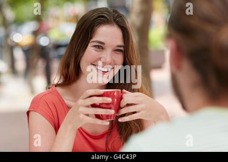 MODEL RELEASED. Young woman drinking coffee with friend. Stock Photo