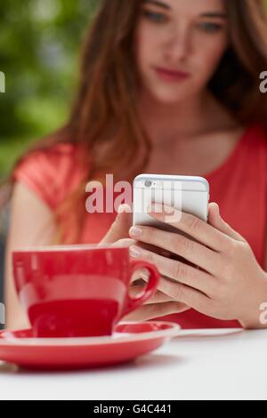 MODEL RELEASED. Woman using smartphone with coffee, close up. Stock Photo
