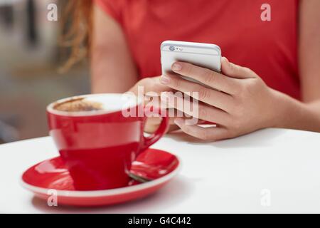 MODEL RELEASED. Person using smartphone with coffee, close up. Stock Photo