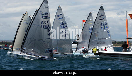 Great Britain's Finn sailor Ben Ainslie (yellow vest) pins his young rival and teammate Giles Scott (red cap) at the back of the fleet on the start line during day six of the Skandia Sail for Gold Regatta in Weymouth, Dorset. Stock Photo