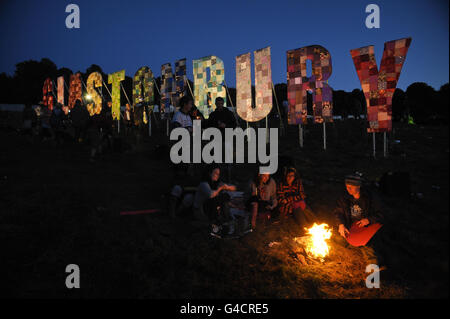 Revellers light a fire after sunset near the Park area at Glastonbury music festival at Worthy Farm, Pilton. Stock Photo