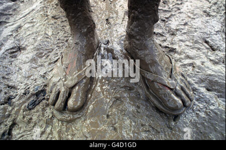 Wellies might have been a better choice of footwear than flip-flops for this very muddy festival-goer at Glastonbury. Stock Photo