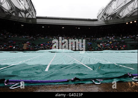The covers are pulled on to Centre Court as rain falls during day eight of the 2011 Wimbledon Championships at the All England Lawn Tennis and Croquet Club, Wimbledon. Stock Photo