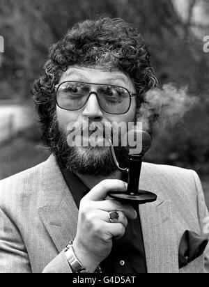 DJ DAVE LEE TRAVIS AT THE SAVOY HOTEL IN LONDON TRIES A PIPE SHAPED INTO A MICROPHONE STANDING ON A RECORD WHERE HE WAS VOTED PIPEMAN OF THE YEAR BY THE TOBACCO INDUSTRY WORKERS Stock Photo
