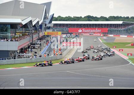 Red Bull Racing's Sebastian Vettel leads the field through the first corner during the Santander British Grand Prix at Silverstone Circuit, Northampton. Stock Photo