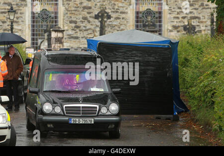 Forensic officers and undertakers load a coffin into a hearse at Urbleshanny graveyard in Scotstown, Co.Monaghan, where they carried out an exhumation after a tip-off that the grave may have been used to bury a teenage IRA victim more than 35 years ago.. Stock Photo