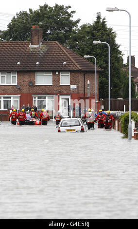 Local residents are rescued by the emergency services from a road in Huyton, Merseyside, after a water main burst causing flooding on roads already wet form heavy rain. Stock Photo
