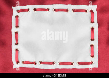 Frame made of white silk with inserted red satin ribbon, on red silk background Stock Photo