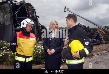 Home Secretary Theresa May talks to firefighters at the burnt out remains of the Sony Distribution Centre in Enfield North London. Stock Photo