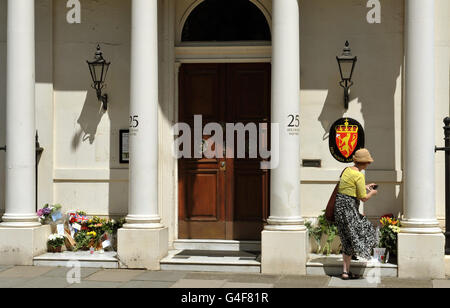 A woman takes a picture of flowers and messages left outside the Royal Norwegian Embassy, in Belgravia central London, following the twin attacks in Oslo in Norway on Friday. Stock Photo