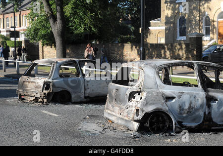 Two burnt out vehicles are seen on St Mary's Road in Ealing following a night of civil unrest on the streets of London. Stock Photo