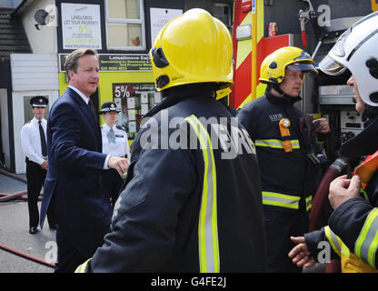 Prime Minister David Cameron talks to fire officers in Croydon, south London today where he saw damage to shops and residences carried out by rioters last night. Stock Photo