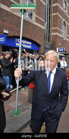 London Mayor Boris Johnson holds a broom aloft as he addresses members of the community outside Clapham Junction railway station following a night of disturbances across London and parts of the UK.