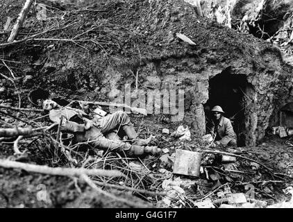 A British soldier gazes out of a dug-out, as the body of a dead German soldier lies nearby at Flers, during the battle of the Somme. Stock Photo