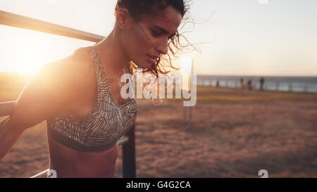 Close up shot of strong young woman exercising on wall bars outdoors. Stock Photo