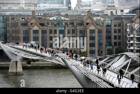 Commuters make their way across the Millennium Bridge over the River Thames in London. Stock Photo