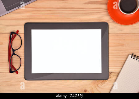 Digital tablet computer with blank screen and cup of coffee on wooden desk. Stock Photo