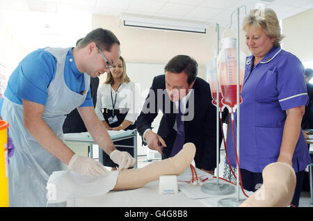 Prime Minister David Cameron watches Peripatetic Assessor William Forster (left) as he demonstrates injecting a needle into a dummy arm during a visit to the Clinical Practice Centre at St James' University Hospital, Leeds. Stock Photo