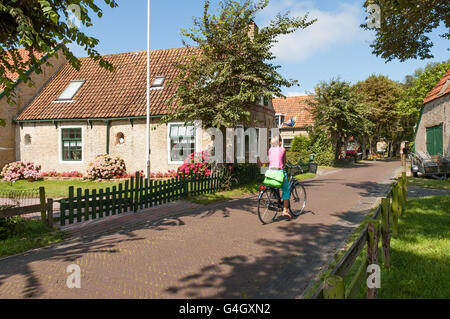 Street scene with woman on bicycle in  historical town Hollum on West Frisian island Ameland, Netherlands Stock Photo