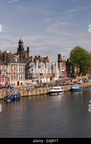 Lots of people drinking & relaxing in sun at busy riverside pubs & leisure boats moored on River Ouse - King's Staith, York, North Yorkshire, England. Stock Photo