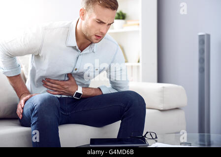 Sick man sitting on the couch Stock Photo