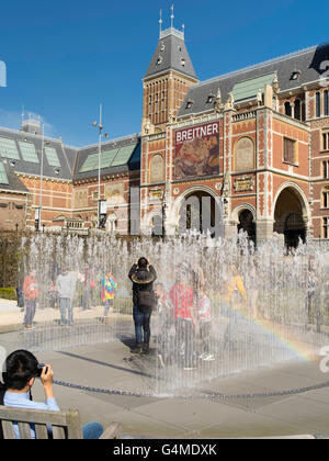 People gather outside Amsterdam's Rijksmuseum to play in a garden fountain on a beautiful spring day. Stock Photo