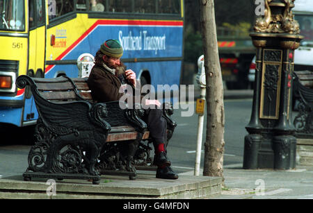 A homeless man rests on a park bench beside a busy London street. 27/03/02 : A homeless man rests on a park bench beside a busy London street. : A grim picture of London as a city of homeless people, yobs and bigots was painted today, in a new Lonely Planet tourist guide. The guide describes the capital's public transport system as an exhausting, debasing grind. The Trafalgar Square pigeons are seen as dirty, flying rats while visitors to Oxford Street have to run the gauntlet of permanent closing down' sales. Stock Photo