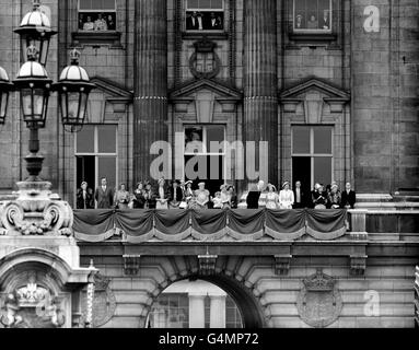 Prince Charles, held by the Queen as he stands on a chair, waves to his mother as she takes the salute in Buckingham Palace forecourt following the Trooping the Colour ceremony. Left to right; fifth from left, The Marchioness of Carisbrooke; Lady Patricia Ramsey; unidentified; the Duchess of Kent; Queen Mary; in front Prince Richard of Gloucester; Prince Charles and the Queen; the Duchess of Gloucester; King Haakon of Norway; and Princess Margaret.