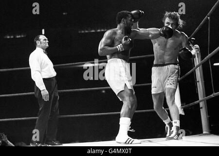 Ex-heavyweight champion of the world, Joe Frazier, left, of the USA, in action against Britain's Joe Bugner. Watching is referee Harry Gibbs. Stock Photo