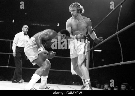 Ex-heavyweight champion of the world, Joe Frazier, left, of the USA, in action against Britain's Joe Bugner. Watching is referee Harry Gibbs. Stock Photo