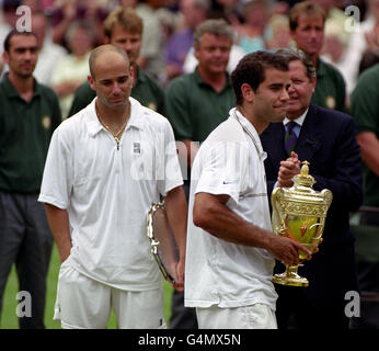 No commercial use. America's Pete Sampras (R) holds the Champion's Trophy, while defeated Andre Agassi looks dejected, after the Men's Singles Final at the 1999 Wimbledon tennis Championships. Sampras defeated Agassi 6-3 6-4 7-5. Stock Photo