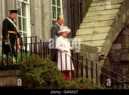 Queen Elizabeth and the Duke of Edinburgh, followed through the grounds of the Palace of Holyrood house by Sir Hew Hamilton-Dalrymple, Captain General of the Royal Archers, at the Queens official residence in Edinburgh. Stock Photo