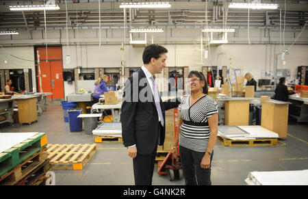 Labour leader Ed Miliband speaks with staff member Shanta Patel, 55, who has been at manufacturing firm Kesslers International for 22 years during his visit to Stratford, east London. Stock Photo