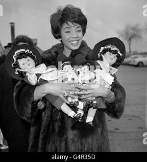 Singer Shirley Bassey has her arms full of dolls in Welsh national costume at London Airport, where she was about to board a Qantas Liner for Australia. On behalf of the Lord Mayor of Cardiff, her native city, she will present the dolls to the towns in which she appears during her Australian tour. Stock Photo