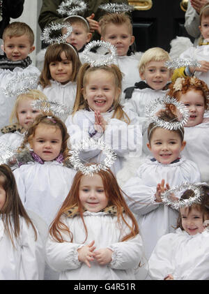Children dressed as angels from St Joseph's Nursery sing Christmas carols, as the traditional Live Animal Crib, supplied by the Irish Farmers' Association, opens at the Mansion House in Dublin. Stock Photo