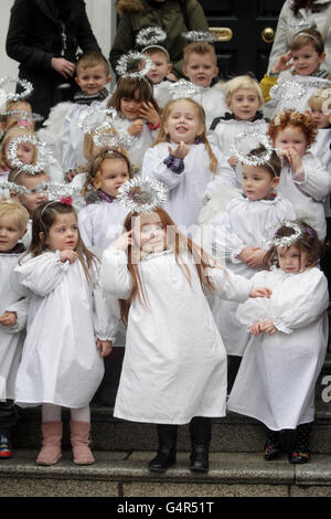 Children dressed as angels, from St Josephs Nursery, sing Christmas carols as the traditional Live Animal Crib, supplied by the Irish Farmers Association, opens at the Mansion House in Dublin. Stock Photo