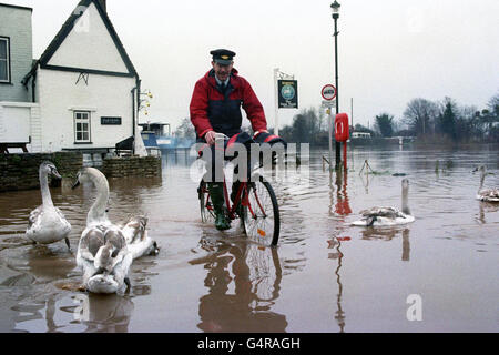 Postman Ray Loveslife-Brown pedals away after delivering to the Swan Hotel at Upton upon Severn. After bursting its banks, water from the nearby river Severn has threatened the hotel for nearly two weeks, forcing closure during the Christmas Period Stock Photo