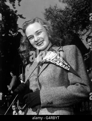 A young woman welcoming Princess Elizabeth and the Duke of Edinburgh to Canada, with a pennant bearing their portraits. Stock Photo