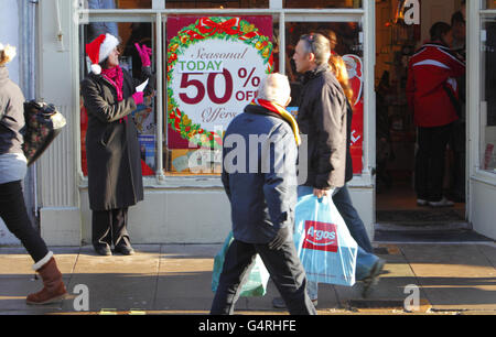 Inspired by Mary Portas' report this week, Diane Parton, Manageress of Past Times in Chichester, West Sussex coaxes Christmas shoppers into her shop by shouting out the special offers to passers by, on what is expected to be one of the busiest shopping days of the year. Stock Photo