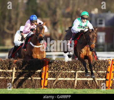 Captain Conan ridden by Barry Geraghty clears the fence on the first circuit behind Colour Squadron ridden by Richard Johnson and goes on to win the 32RED Hurdle Race during the 32RED Hurdle Day with Comedy at the Races at Sandown Racecourse, Esher. Stock Photo