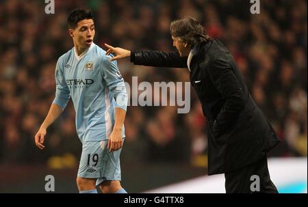 Soccer - Carling Cup - Semi Final - First Leg - Manchester City v Liverpool - Etihad Stadium. Manchester City's Samir Nasri (left) is given directions by manager Roberto Mancini as he is sustituted on Stock Photo