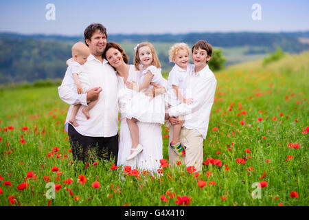 Big happy family with four children in red poppy flower field. Stock Photo