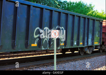 A Canadian Pacific freight train as it passes a sign notifying train engineers that they are not to use locomotive horns. Bartlett, Illinois, USA. Stock Photo