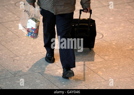 A passenger pushes his bags through terminal 5 of Heathrow Airport Stock Photo
