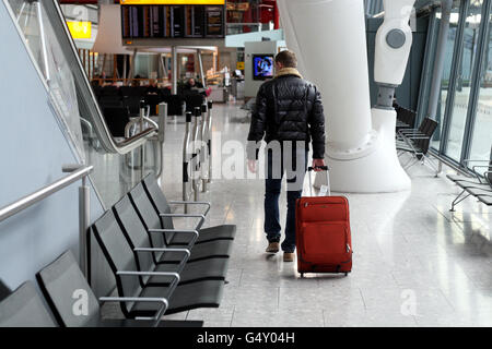 Heathrow - London. A passenger pushes his bags through terminal 5 of Heathrow Airport Stock Photo