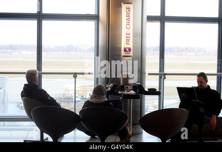 Heathrow - London. Passengers sit at a free charging point for ...