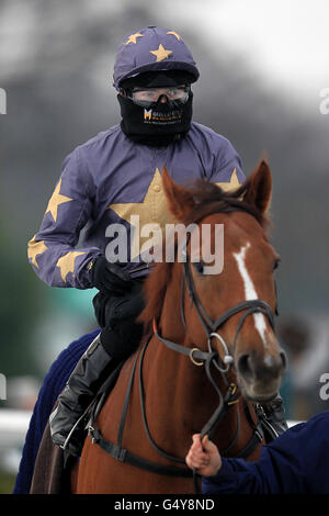 Jockey Jamie Spencer wears a snood and a pair of goggles as he is lead around the parade ring on Drawnfromthepast Stock Photo